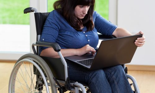 Woman in a wheelchair typing on a laptop.