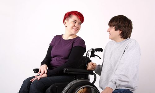 Photo of s young man and woman. The young woman is using a wheelchair.
