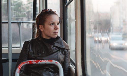 Photo of a woman sitting on a bus looking out the window.
