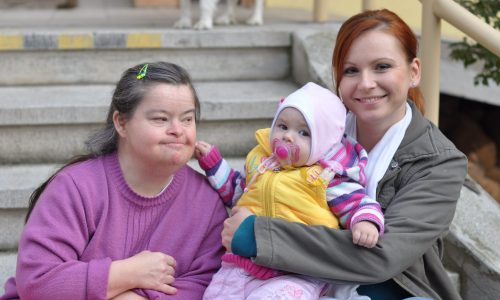 Photo of two women and a baby sitting on steps.