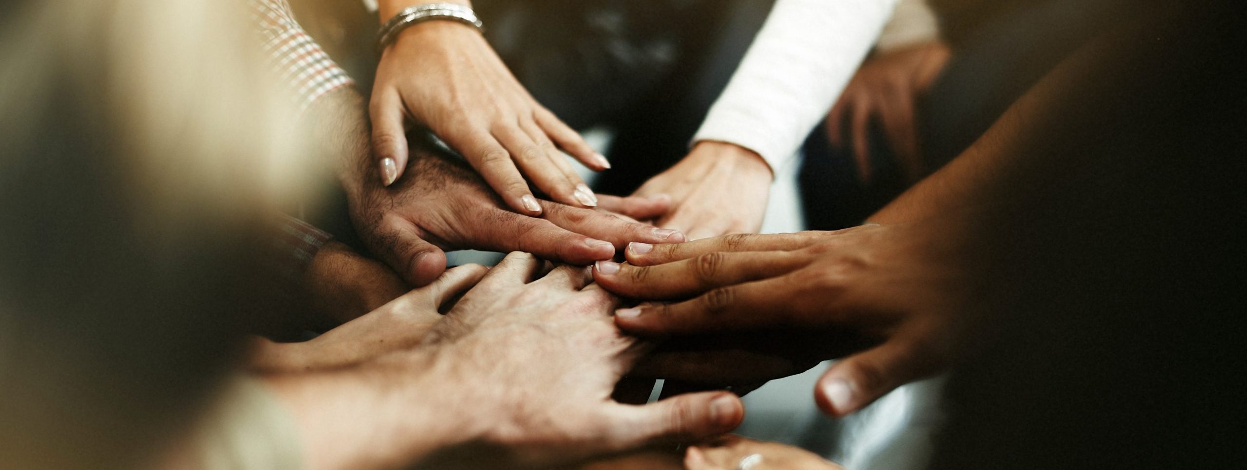 Photo of people standing in a circle and putting their hands together