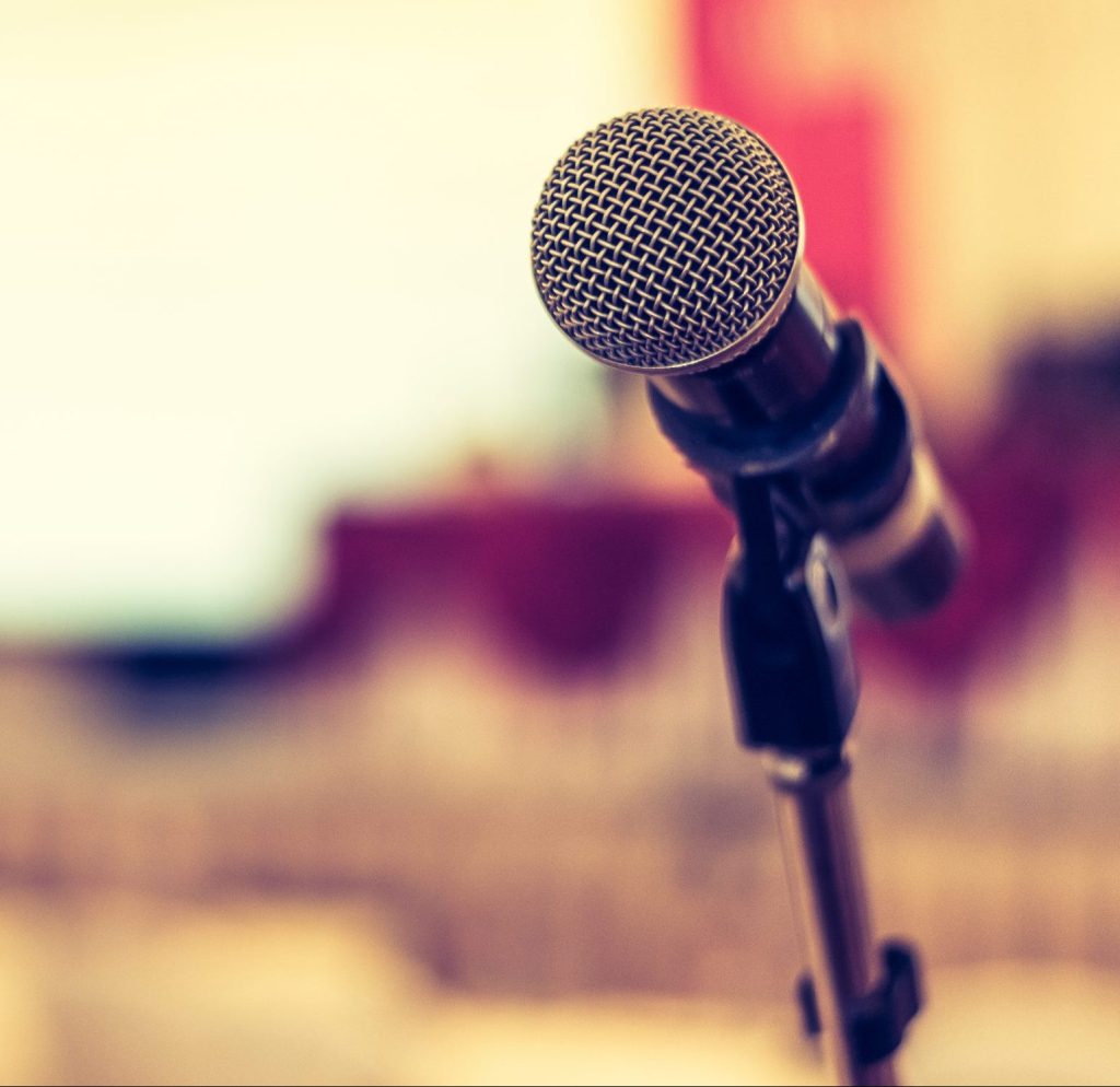 Photo of microphone with a seminar room in the background.