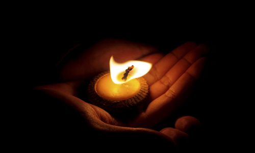 Photo of a candle sitting in the palm of a hand.