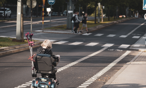 Photo of a person using a motorised wheelchair moving along a bike lane on a road