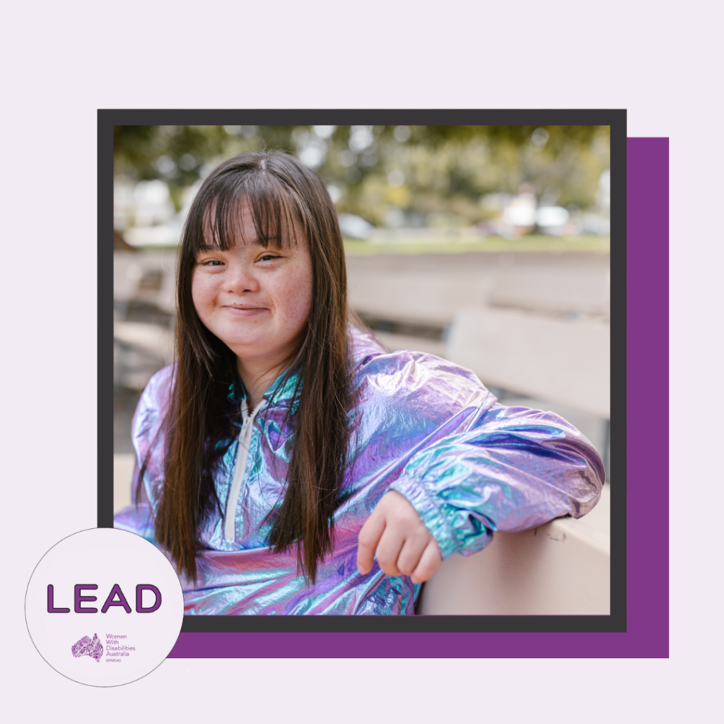 [Image: Light purple background with a dark purple shadow, the photo has a black border, the LEAD logo is in the left-hand corner and text says ‘LEAD Women With Disabilities Australia (WWDA), the photo is of a young woman with disability, she has long brown hair, wearing a blue and purple shiny top and is smiling.]