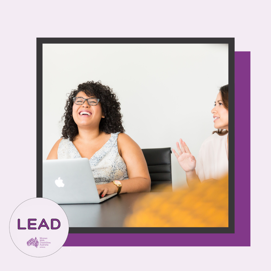 [Image: Light purple background with a dark purple shadow, the photo in the centre is surrounded by a black border, the LEAD logo is in the bottom left corner and text reads ‘LEAD Women With Disabilities Australia (WWDA)’, the photo is of two women talking to each other, one of the women is behind her laptop and she has dark curly hair and is laughing, the woman to her right has dark brown hair and has her hand up.]