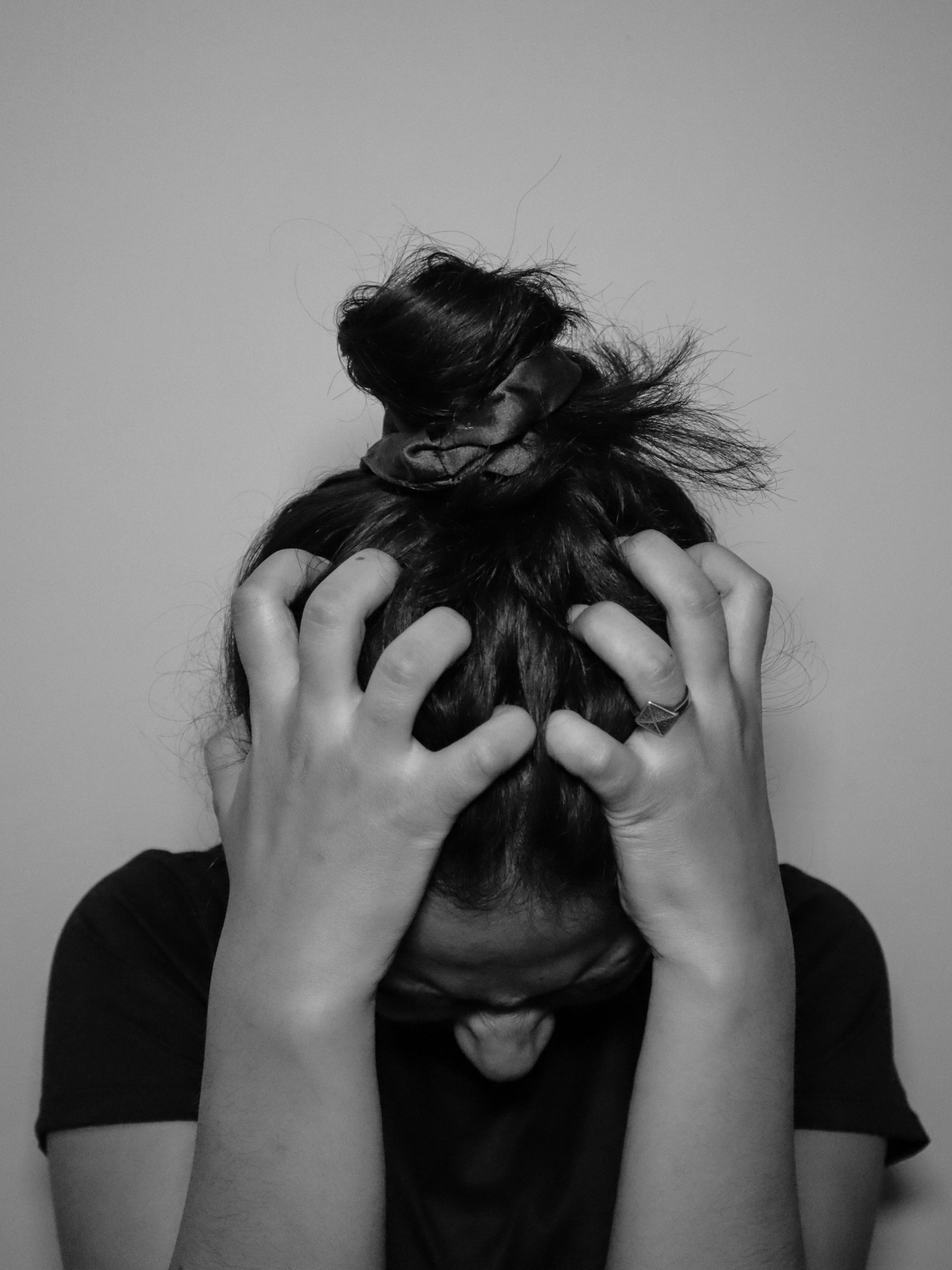 a stock image of a woman with her hair tied up in a messy bun and she is scrunching her hair on her head. The photo is in black and white.