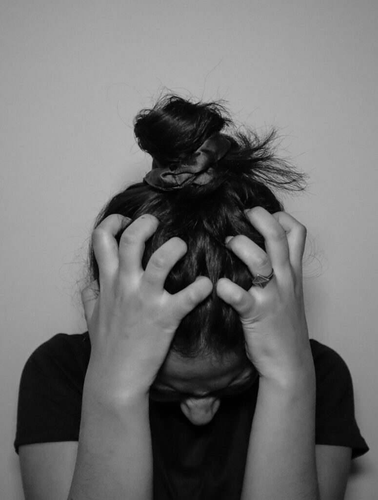 a stock image of a woman with her hair tied up in a messy bun and she is scrunching her hair on her head. The photo is in black and white.